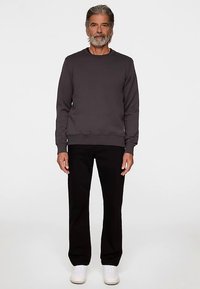 Mörkgrå sweatshirt med rund hals och ribbstickade muddar; kombinerad med svarta byxor och vita sneakers; slät textur; avslappnad passform.