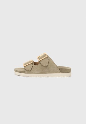 Sandales en suède khaki avec deux sangles ajustables et boucles en ton doré, dotées d'une semelle plate et d'un rembourrage texturé pour le confort.