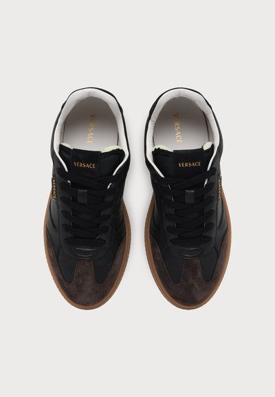 Paire de baskets Versace noires et marron avec semelles en gomme, lacets noirs et doublure intérieure blanche vue de dessus.