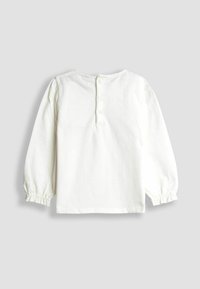 Fehér, hosszú ujjú kisgyermeking, hátul gombos záródással és rugalmas, redőzött mandzsettákkal, sík felületen bemutatva.