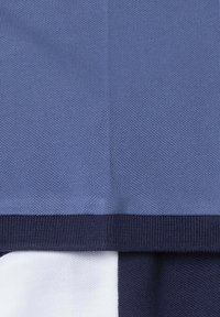 Pull en maille montrant un mélange de sections bleu clair et bleu foncé. Il présente une finition texturée et un ourlet côtelé marine contrastant.