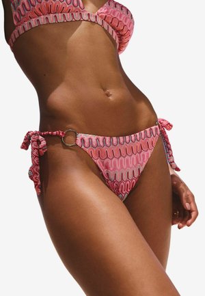 Růžový vzorovaný bikini s vlnitým designem, zavazování na bocích, s kovovým kroužkem jako akcentem. Materiál vypadá texturovaně a lehce.