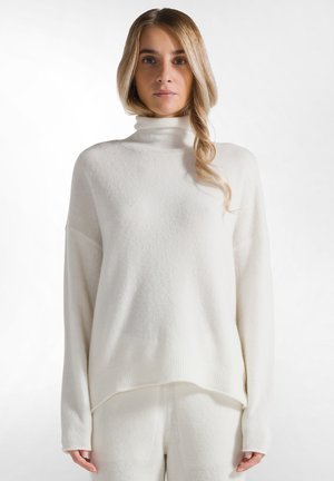 Long-sleeve white turtleneck sweater made of soft, textured knit fabric with a relaxed fit and ribbed hem detailing.