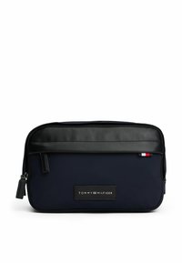 Beauty case in tessuto blu navy con parte superiore in pelle nera, chiusura con zip e una toppa con logo. Presenta una piccola striscia di accento rossa, bianca e blu.