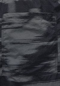 Tmavá látková kapsa s abstraktním vzorem šedých a černých štětcových tahů, viditelné švy podél okrajů.