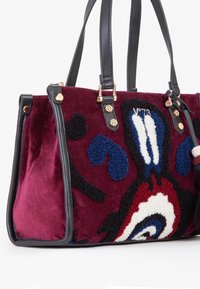 Borsa strutturata in tessuto borgogna con dettagli in pelle nera. Presenta un design floreale in blu, rosso e bianco. Dettagli in metallo dorato.