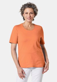 Oranje T-shirt met korte mouwen van katoen, met een ronde hals en een soepele textuur, gecombineerd met witte broek.