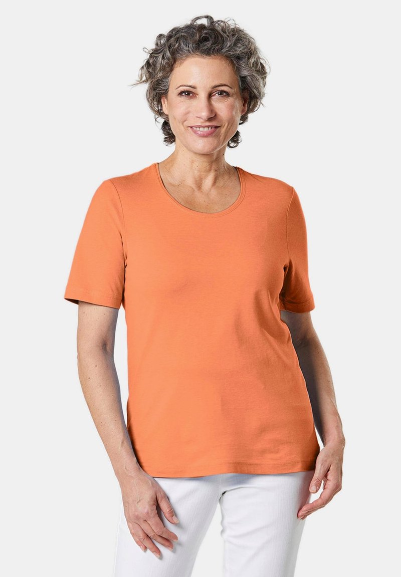 Oranje T-shirt met korte mouwen van katoen, met een ronde hals en een soepele textuur, gecombineerd met witte broek.