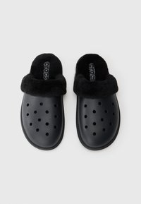 Crne klompe na slip-on s ventilacijskim rupama i mekim, pahuljastim obodom oko otvora, s natpisom "Crocs" na đonu.