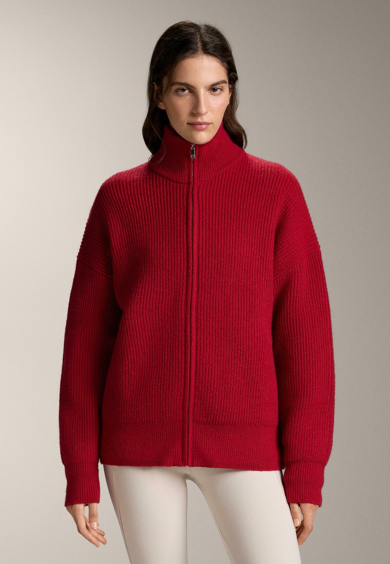 Rode geribbelde trui met hoge kraag en rits over de volle lengte. Voorzien van oversized mouwen en een ontspannen pasvorm. Gemaakt van textuurgaren.