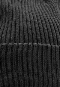 Black ribbed knit fabric with vertical stripes and a soft, textured surface. Close-up view highlights the warmth and flexibility of the material.