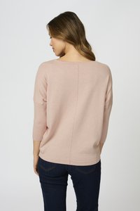 Svetlo roza pletena pulover s tričetrtnimi rokavi, širokim izrezom in subtilno šivno podrobnostjo na hrbtu. V kombinaciji z temnimi kavbojkami.