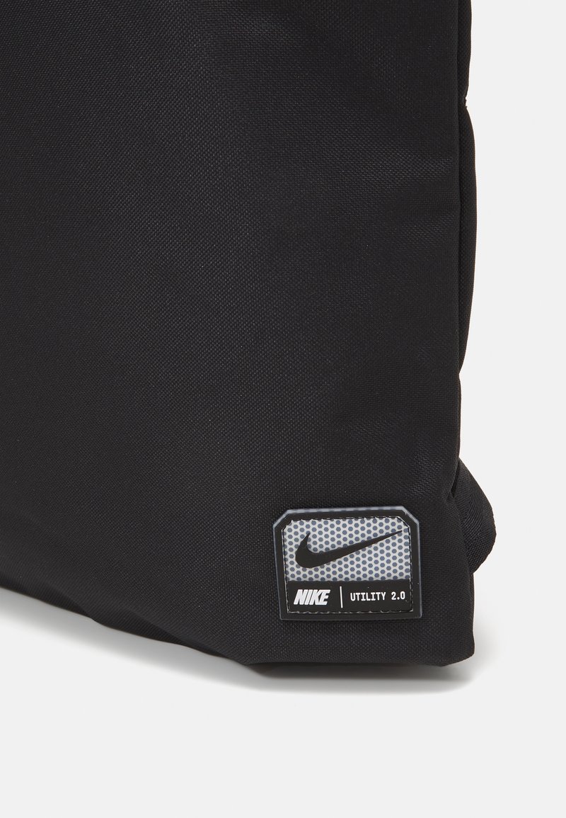 Czarna torba Nike Utility 2.0 z teksturowanej tkaniny, z prostokątną łatą logo w szaro, z wzorem kropek i czarnym napisem.