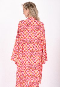 Kimono colorido con un patrón floral en tonos de rosa, naranja y amarillo. Confeccionado en una tela ligera, presenta mangas anchas y un corte holgado.