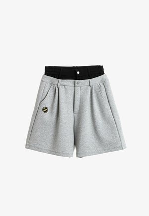 Dos pares de pantalones cortos, uno gris con botón y trabillas para cinturón, y uno negro con cintura elástica superpuestos, sobre un fondo blanco.