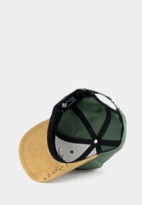 Grüne Stoffmütze mit einem hellbraunen Wildlederschirm. Verfügt über ein schwarzes Innenfutter, Belüftungslöcher und ein mehrteilige Design. Innenschild sichtbar.