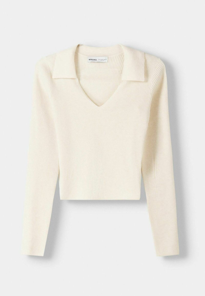 Maglione a maniche lunghe in crema a coste con scollatura a V e colletto a punta. Il design presenta una lunghezza cropped e un materiale testurizzato.