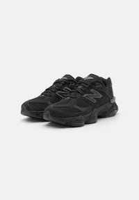 Chaussures de sport noires avec une tige en mesh et en daim, des accents texturés, un col rembourré et une semelle en caoutchouc. Dotées d'éléments réfléchissants pour plus de visibilité.