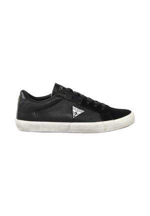 Zwarte lage sneaker met witte rubberen zool, vetersluiting en Guess driehoeklogo op het zijpaneel, getoond in het linkerdeel.