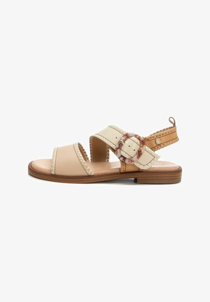 Sandalias de cuero beige con dos correas anchas, acentos trenzados y una hebilla decorativa. Suela plana con un acabado de madera natural.