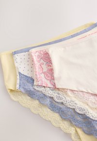 Patru lenjerii de damă pliate în galben pastel, alb, roz floral și albastru cu buline, cu dantelă, pe un fundal neutru.