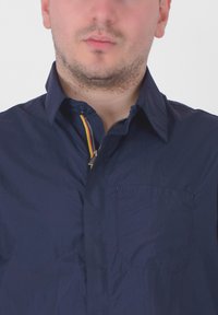 Camicia navy con bottoni, colletto con zip e dettagli colorati, taschino sul petto; tessuto morbido e materiale leggero.