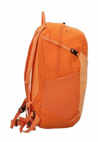 Mochila naranja con una mezcla de tejidos texturizados y suaves, correas ajustables y un bolsillo lateral. El diseño enfatiza la funcionalidad.