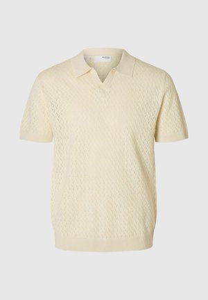 Short-sleeved pullover in light cream, featuring a V-neck and textured pattern with diamond shapes, crafted from knitted material.