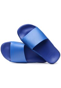 Zilas gumijas slidiens apavi ar platu siksnu pa virsu, teksturētu kājām un gludu virsmu. Viegla un elastīga konstrukcija.