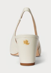 Kreem värvi nahast kontsad, millel on külgedel lõikega disain. Sisel on kuldne "RL" logo kontsal ja pruun talla osa. 2,5-tollised plokkninad.