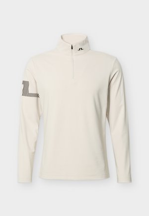 Kreemikas pikkade varrukatega pullover, millel on veerand lukuga avaus, kõrge krae ning vasakul varrukal mustriga triibuline logo ning krae lähedal väike logo.