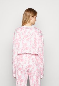 Sweatshirt cropped em tie-dye rosa e branco com mangas longas, apresentando um corte descontraído e textura suave. A vista traseira destaca o design.