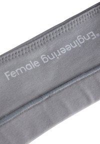 Grå stoftalje med teksten "Kvinde fitting" trykt foran. Glat tekstur og elastisk syning detail.