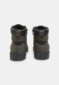 Stivaletti alla caviglia grigio scuro in suede e materiale sintetico, con chiusura a zip laterale e una suola in gomma testurizzata.