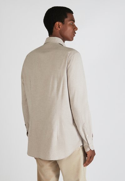 Licht beige langarm overhemd met een kraag, gladde textuur en met knopen afgesloten mouwen. De achterkant heeft een middennaad en een afgeronde zoom.