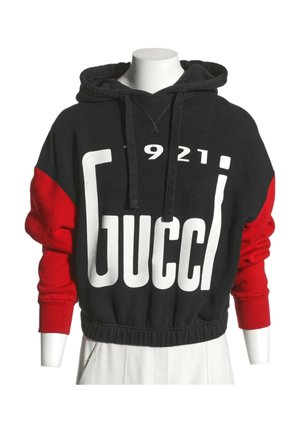 Czarna i czerwona bluza z kapturem z dużym białym napisem "Gucci" i liczbami "1921" z przodu, prezentowana na białym torsie manekina.