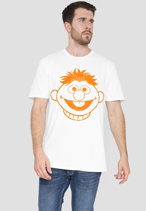 White cotton t-shirt featuring a large orange graphic of a cartoon character's face with prominent eyes, a big smile, and spiky hair.