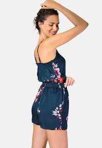 Rompers fleuris en tissu bleu foncé avec une taille smockée, des bretelles fines et des motifs floraux vifs. Texture douce avec une coupe ample.