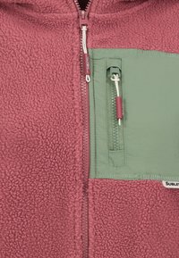 Fleece jack in bordeaux met een groene nylon borstzak, voorrits en trekkoord. Getextureerde stof met contrasterende kleuraccenten.