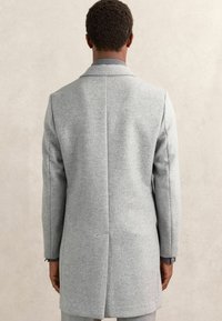 Helehall villane mantel, millel on kohandatud disain, sisselõigetega krae ja sile tekstuur. Kitsas lõige, ühekordse tuuleaugu detailiga taga.