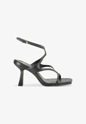 Sandales à talons noires au design épuré, dotées de fines lanières et d'une boucle à la cheville. Tige en cuir texturé et forme de bout carrée.