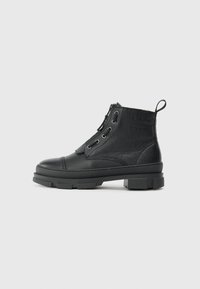 Botas de cuero negras hasta el tobillo con un acabado texturizado, punta redonda y suela de goma con tacos. Incluye un diseño de cordones y una lengüeta en la parte trasera.