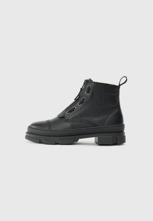 Botas de cuero negras hasta el tobillo con un acabado texturizado, punta redonda y suela de goma con tacos. Incluye un diseño de cordones y una lengüeta en la parte trasera.