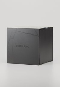 Boîte rectangulaire noire avec une finition mate, arborant un motif de design subtil et le texte "D1 MILANO" en gras sur un côté.