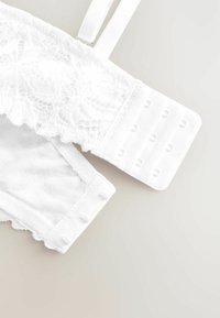 Bijela čipkasta braletica s podesivim trakama, koja se ističe cvjetnim čipkastim dizajnom, mrežastim panelima i zatvaranjem na kuke i očice.