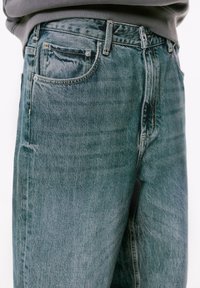 Svijetloplave traperice, visokog struka, s pet džepova, laganim izblijeđenjem i kontrastnim šavovima.