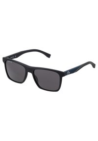 Ochelari de soare negri cu un finisaj mat, formă pătrată, lentile întunecate și accente texturate albastre pe tâmple, având logo-ul Lacoste.