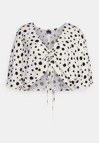 Blusa cropped em tecido leve com fundo branco e grandes bolinhas pretas. Apresenta um decote em V profundo e cordão ajustável na frente.