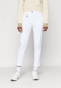 Hvite bukser med slim passform, med knappelukking foran, beltehull og et lite hjerteformet smykke. Glatt tekstur, minimalistisk design.