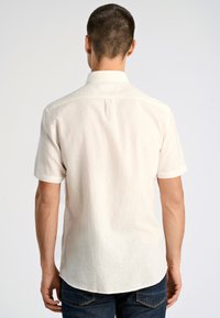 Kortärmad, ljusbeige skjorta i linne. Har en krage, avslappnad passform och en rundad nederkant med en bakfåra för extra komfort.